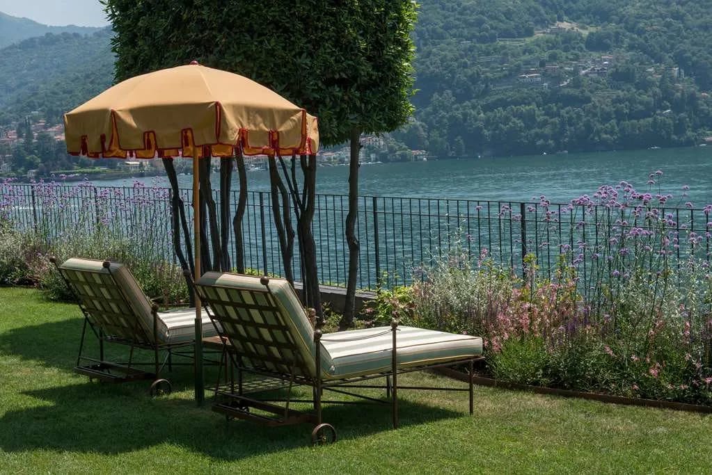Two loungers sit beneath an umbrella, positioned to look out over Lake Como