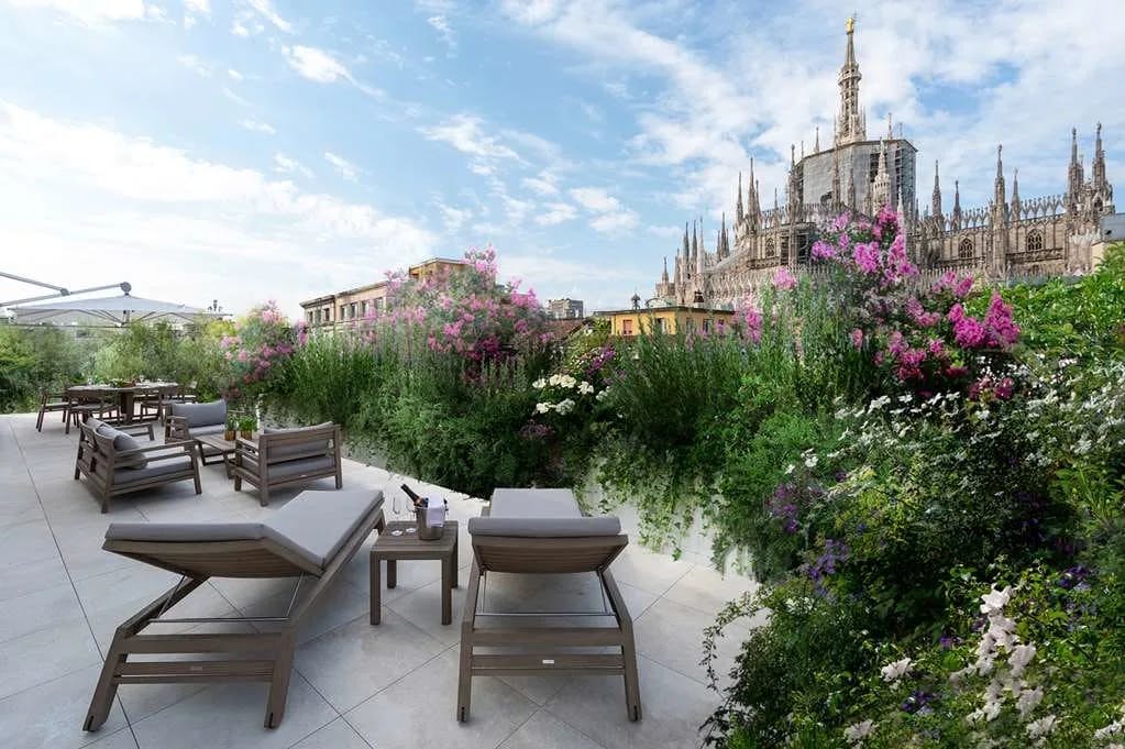 Loungers and Champaigne-topped tables look out toward a flower garden where Milanese architecture juts into the sky