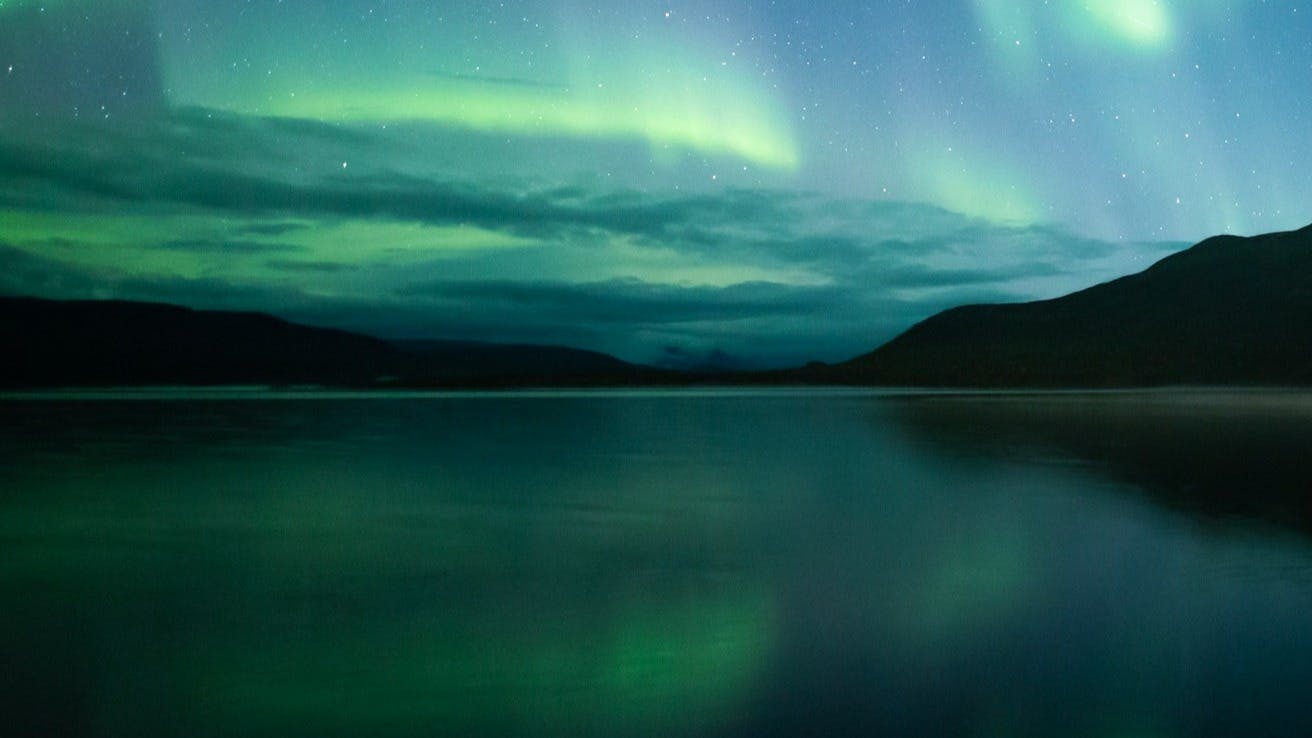 The spectacular Northern Lights in different shades of green and blue above the ocean